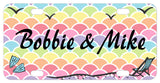 pastel waves of mermaid scales background with flippers, beach chair and birds on a custom license plate personalized with any name or custom text.