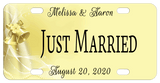 soft yellow goldish background with wedding bells, lace and pearls on the left of the plate and personalized text on top, center and bottom of license plate. Center says Just Married but can be custom printed with any text