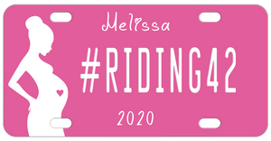 Pink Background with silhouette of a pregnant woman with a pink heart in her belly. Our sample reads #riding42 in the center with name on top and year on bottom. You can personalize with any text in all three areas