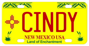 New Mexico mini license plate with zig zag along top and yucca plates in the bottom corners. Bottom says New Mexico USA in red and Land of enchantment in Green. Your choice of font and color for your name in the center