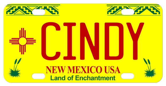 New Mexico mini license plate with zig zag along top and yucca plates in the bottom corners. Bottom says New Mexico USA in red and Land of enchantment in Green. Your choice of font and color for your name in the center